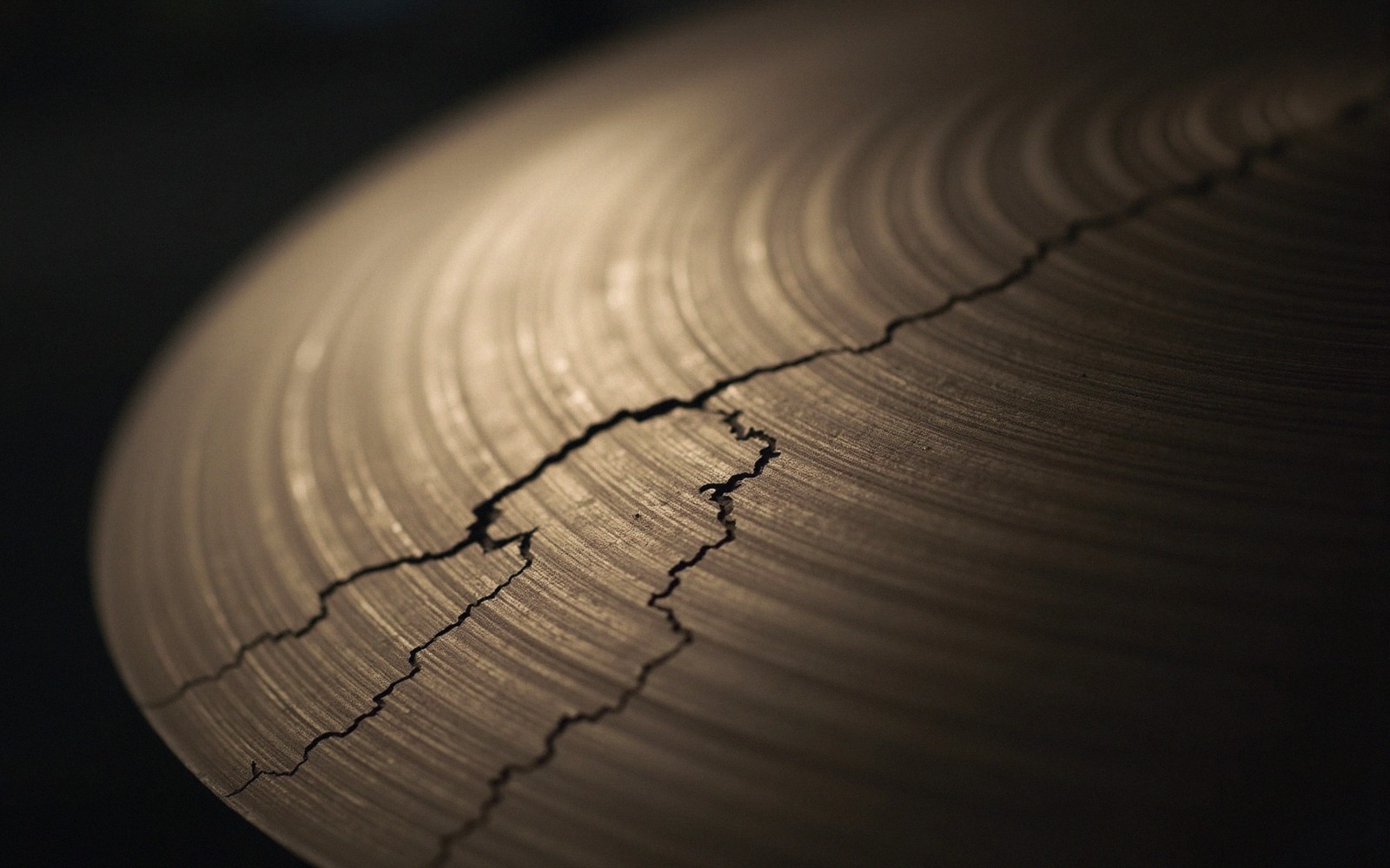 a cracked cymbal edge in hard light, macro